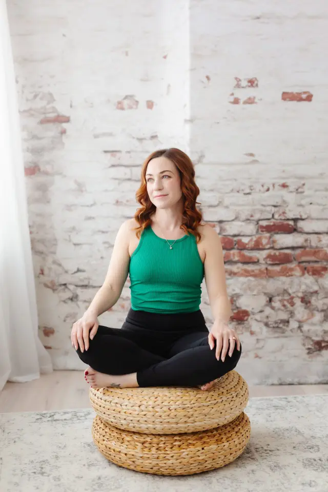 A person seated cross-legged in a calm indoor setting, eyes closed, practicing mindfulness meditation.